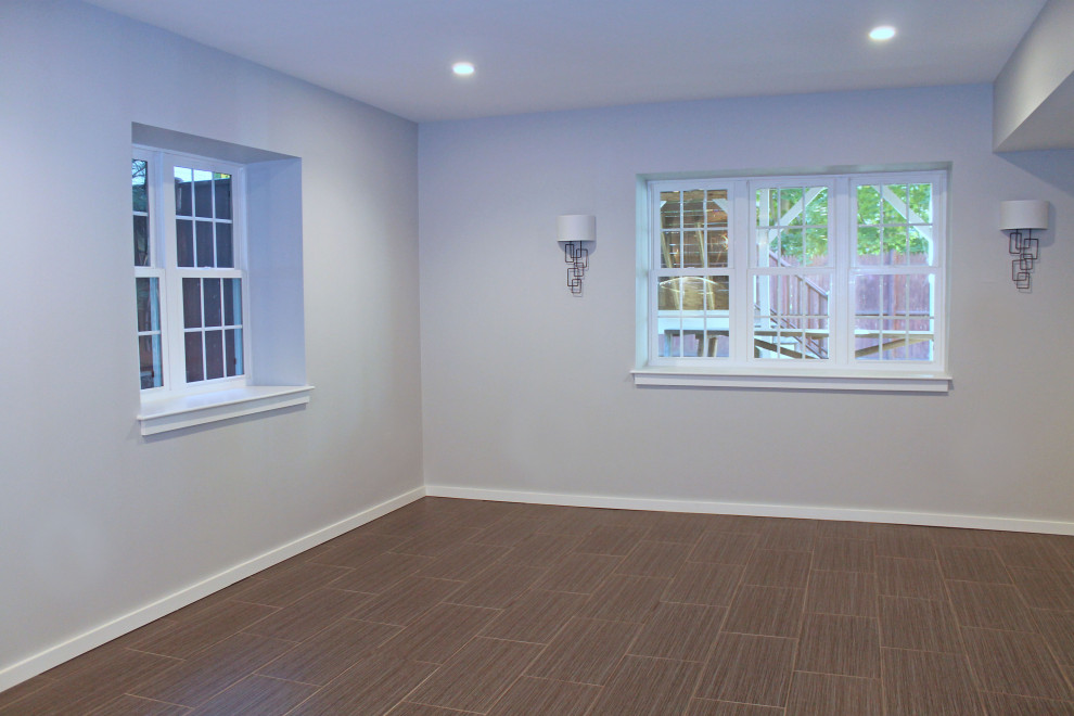 This is an example of a mid-sized transitional walk-out basement in Boston with a home bar, grey walls, ceramic floors and black floor.