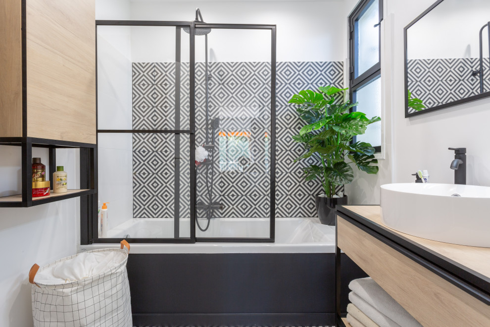 Design ideas for a small contemporary master bathroom in Nice with an undermount tub, a shower/bathtub combo, black and white tile, cement tile, wood benchtops, a sliding shower screen, a single vanity, a floating vanity, a two-piece toilet, white walls, cement tiles and a console sink.