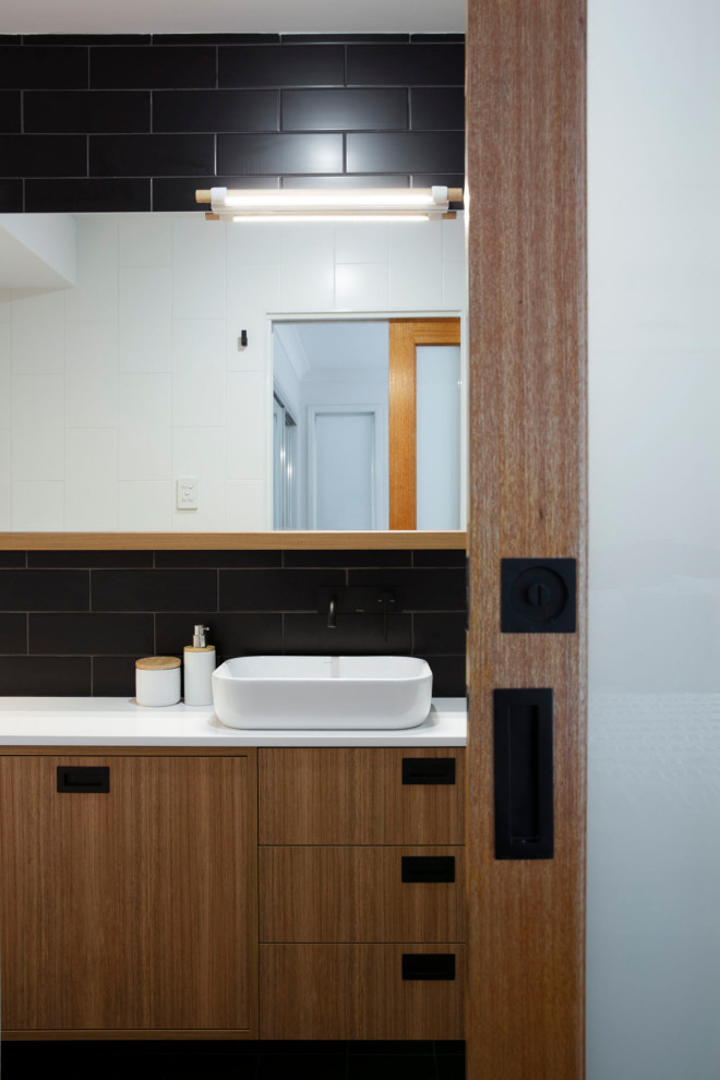 Mid-sized contemporary kids bathroom in Brisbane with light wood cabinets, a freestanding tub, an open shower, a one-piece toilet, black tile, porcelain tile, black walls, porcelain floors, engineered quartz benchtops, grey floor, an open shower and white benchtops.