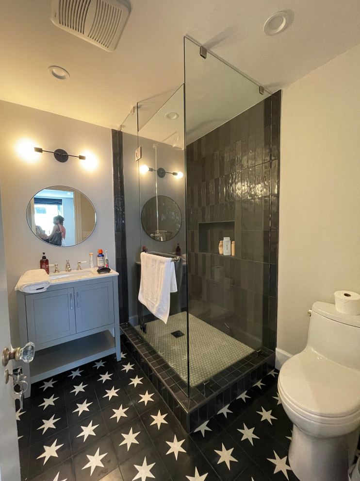 Пример оригинального дизайна: маленькая ванная комната, совмещенная с туалетом в стиле ретро с фасадами в стиле шейкер, серыми фасадами, душем, черно-белой плиткой, плиткой, белыми стенами, полом из цементной плитки, душевой кабиной, врезной раковиной, столешницей из гранита, черным полом, душем с распашными дверями, белой столешницей, нишей, тумбой под одну раковину, напольной тумбой, любым потолком и любой отделкой стен для на участке и в саду
