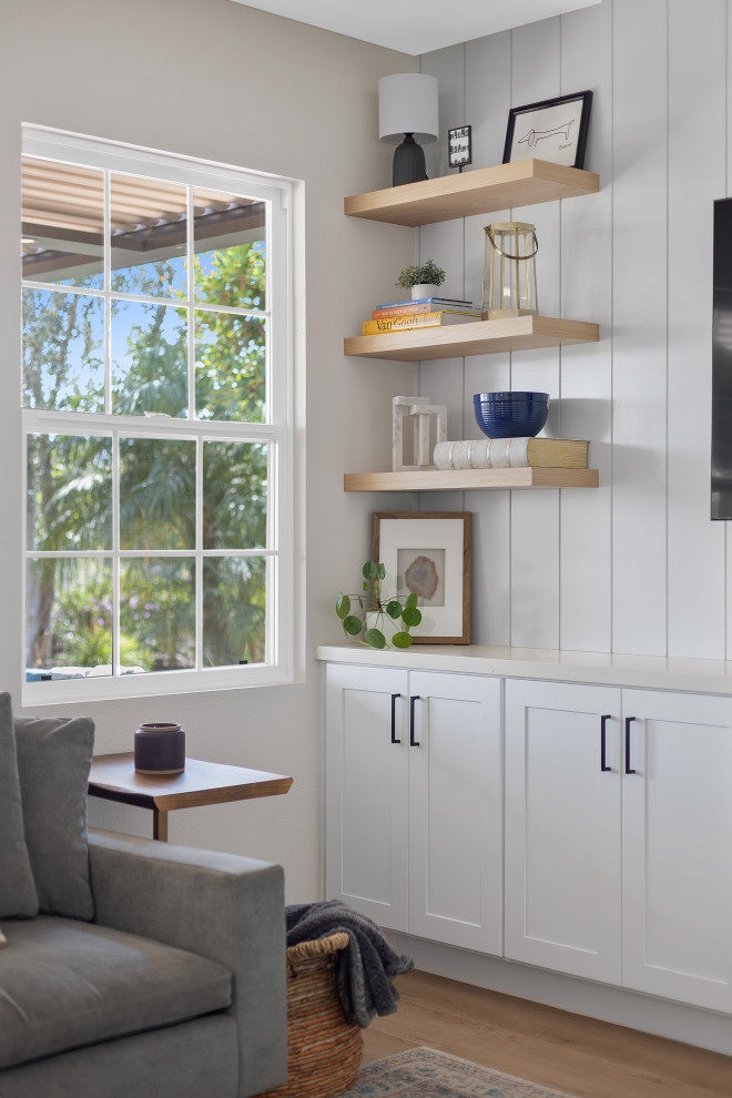 Imagen de sala de estar minimalista de tamaño medio sin chimenea con paredes blancas, suelo de madera en tonos medios, televisor colgado en la pared, suelo marrón y machihembrado