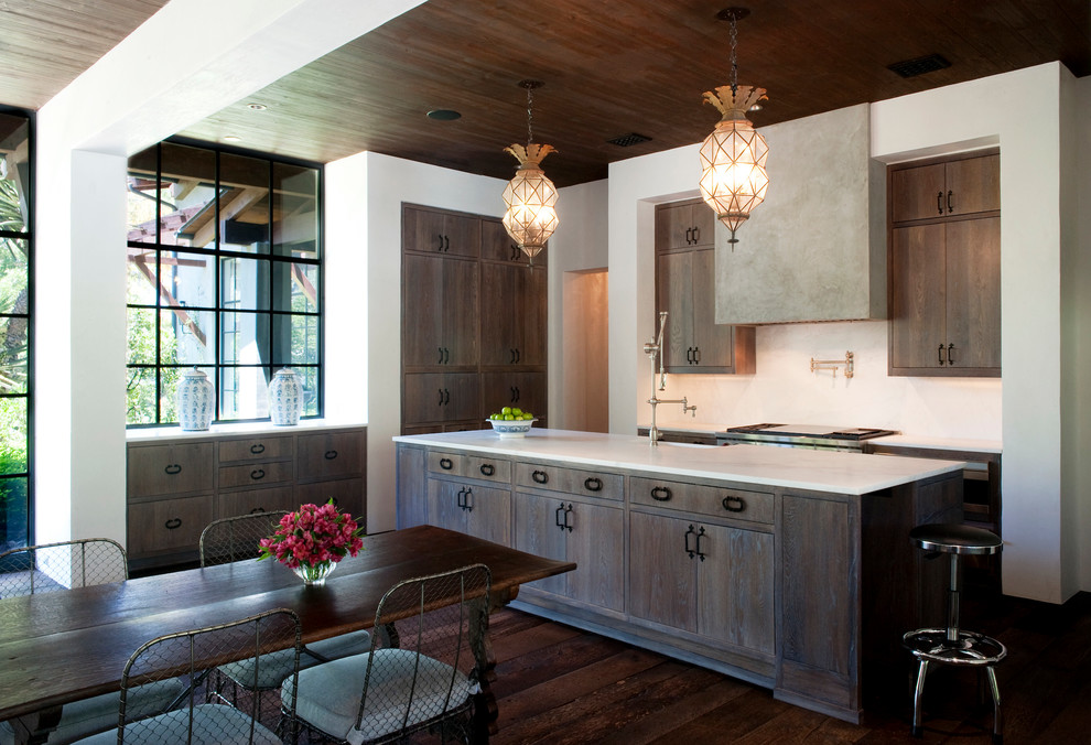 Inspiration for a mid-sized arts and crafts l-shaped eat-in kitchen in Austin with a farmhouse sink, flat-panel cabinets, stainless steel appliances, dark hardwood floors, with island, dark wood cabinets, quartz benchtops and brown floor.