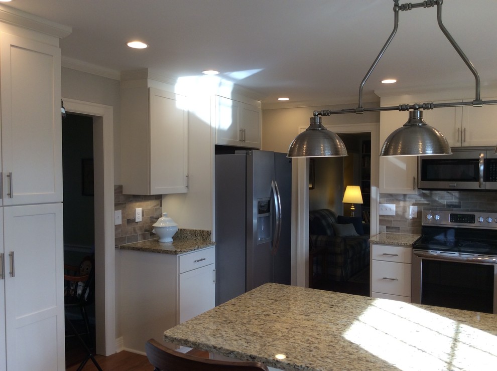 Kitchen - transitional u-shaped medium tone wood floor kitchen idea with an undermount sink, shaker cabinets, white cabinets, granite countertops, beige backsplash, subway tile backsplash, stainless steel appliances and a peninsula