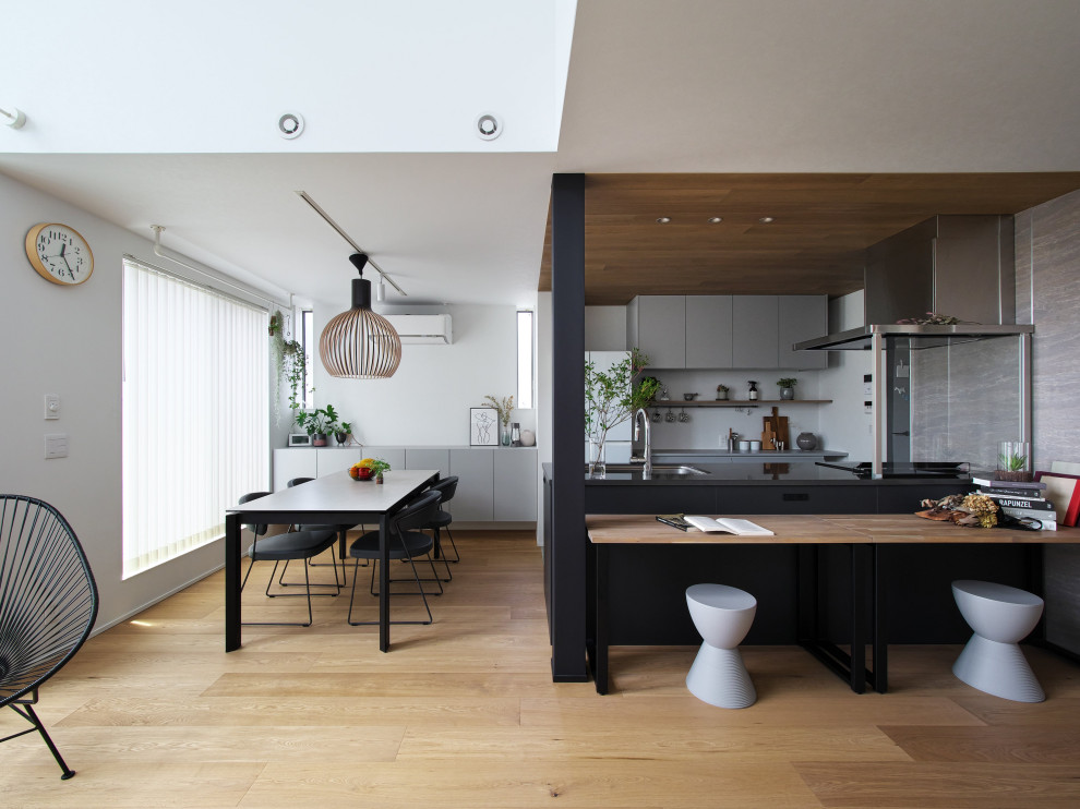This is an example of a modern open plan dining room in Osaka with white walls, medium hardwood flooring, no fireplace, a wallpapered ceiling, wallpapered walls and feature lighting.