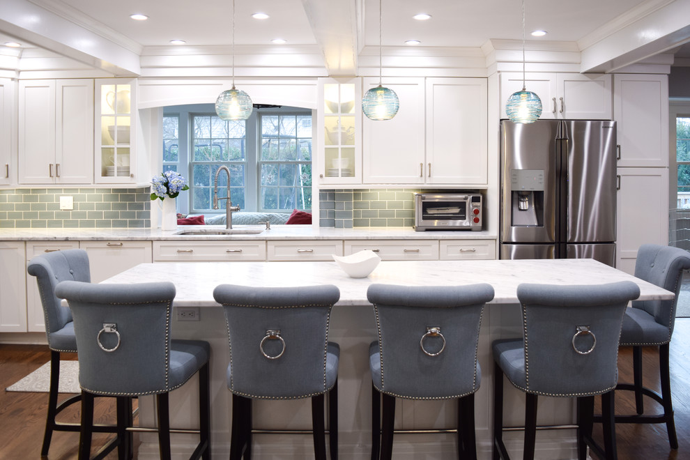 This is an example of a large beach style l-shaped eat-in kitchen in New York with an undermount sink, shaker cabinets, white cabinets, marble benchtops, blue splashback, subway tile splashback, stainless steel appliances, medium hardwood floors and with island.