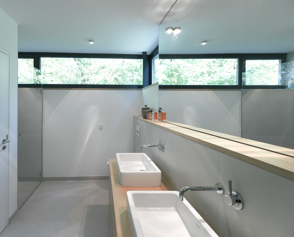 Mid-sized modern bathroom in Hamburg with a vessel sink, wood benchtops, gray tile, white walls and stone slab.