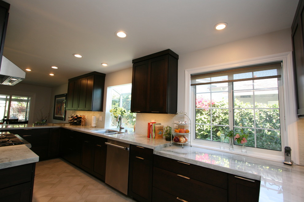Kitchen - mid-sized transitional l-shaped porcelain tile kitchen idea in Orange County with a double-bowl sink, recessed-panel cabinets, dark wood cabinets, quartzite countertops, white backsplash, glass tile backsplash, stainless steel appliances and no island