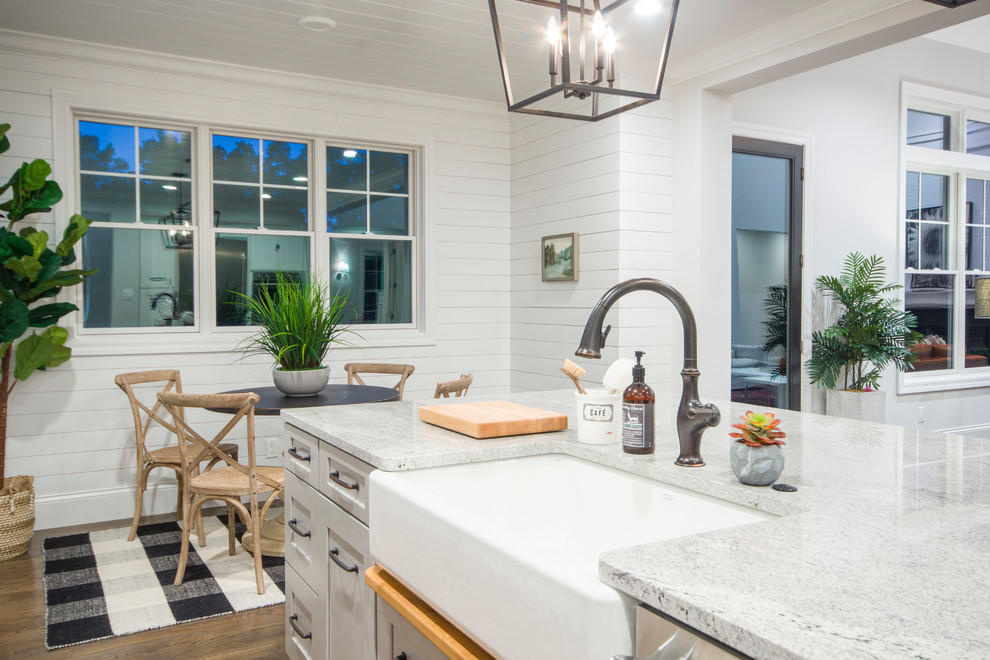 Open concept kitchen - large contemporary galley dark wood floor and brown floor open concept kitchen idea in St Louis with a double-bowl sink, flat-panel cabinets, white cabinets, marble countertops, black appliances, an island and white countertops