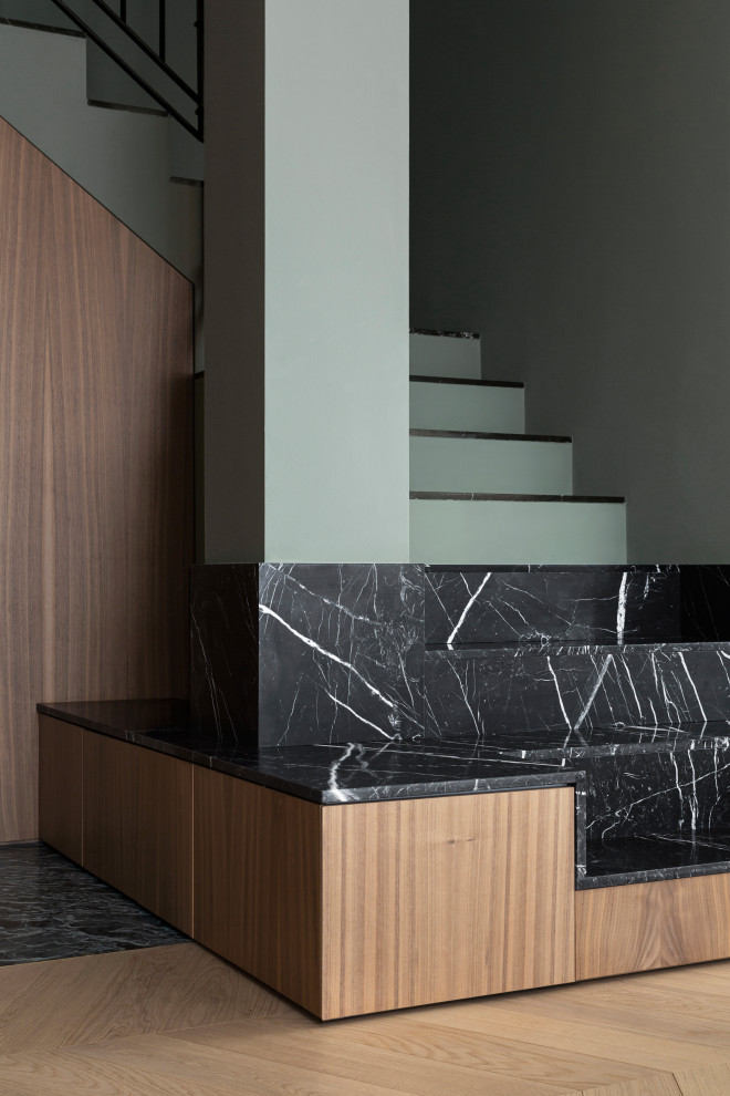 Esempio di una scala a "U" minimal di medie dimensioni con pedata in marmo, alzata in cemento, parapetto in metallo, boiserie e decorazioni per pareti