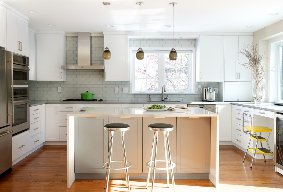 Inspiration for a mid-sized transitional u-shaped medium tone wood floor and brown floor eat-in kitchen remodel with an undermount sink, shaker cabinets, white cabinets, quartz countertops, glass tile backsplash, stainless steel appliances, beige walls, gray backsplash and an island