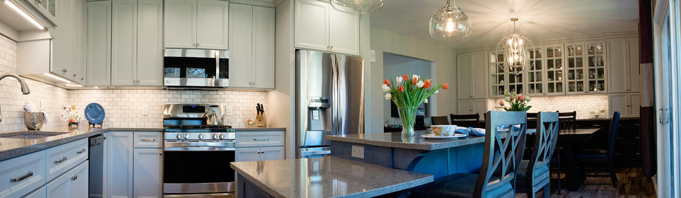 Mid-sized transitional l-shaped vinyl floor eat-in kitchen photo with an undermount sink, recessed-panel cabinets, gray cabinets, quartz countertops, white backsplash, marble backsplash, stainless steel appliances and an island