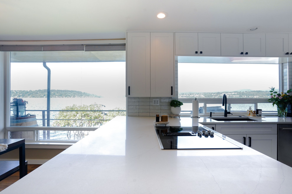 This is an example of a small modern u-shaped eat-in kitchen in Seattle with an undermount sink, white cabinets, granite benchtops, white splashback, ceramic splashback, stainless steel appliances, with island and white benchtop.