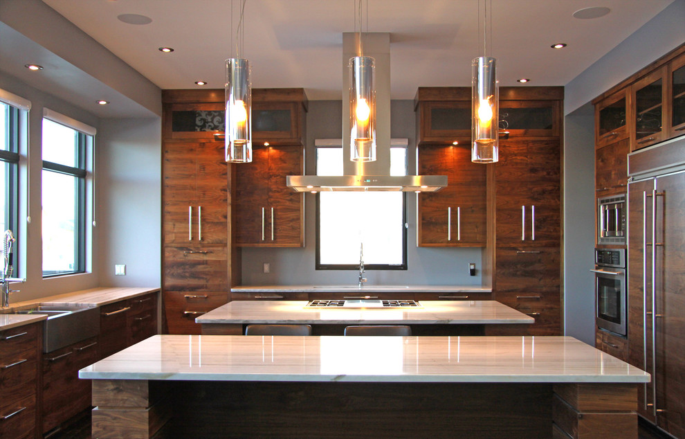 Photo of a large contemporary u-shaped open plan kitchen in Other with a drop-in sink, flat-panel cabinets, medium wood cabinets, marble benchtops, panelled appliances, dark hardwood floors, multiple islands, white splashback and stone slab splashback.
