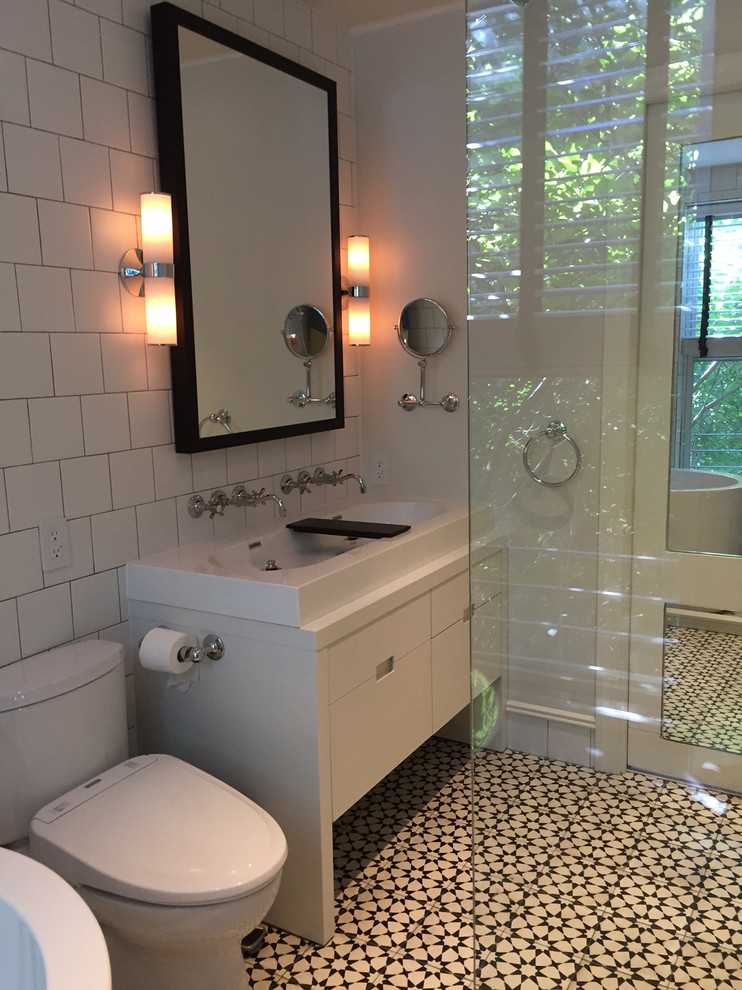 Inspiration for a mid-sized modern master bathroom in New York with flat-panel cabinets, white cabinets, a japanese tub, an open shower, a bidet, white tile, white walls, solid surface benchtops, ceramic tile, cement tiles and a trough sink.