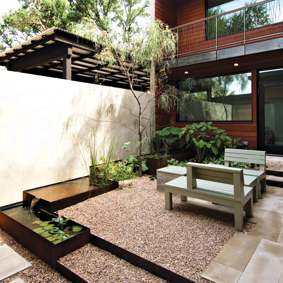 This is an example of a mid-sized contemporary courtyard partial sun formal garden in Austin with a water feature and gravel.