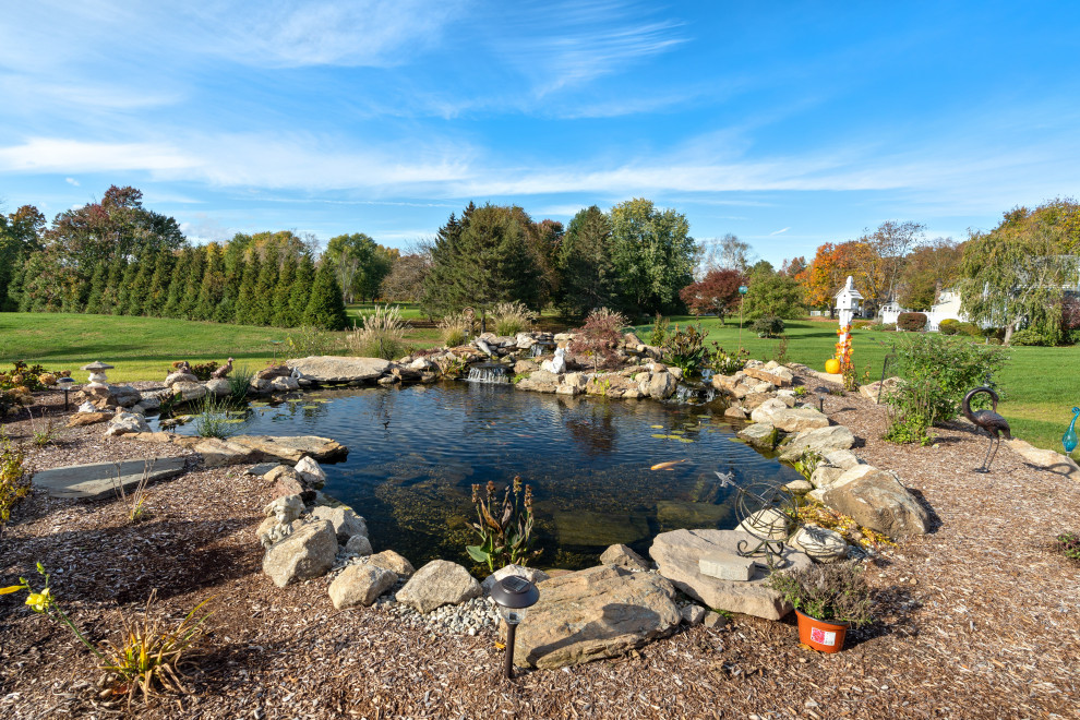 Ispirazione per un grande laghetto da giardino country esposto in pieno sole dietro casa con sassi di fiume