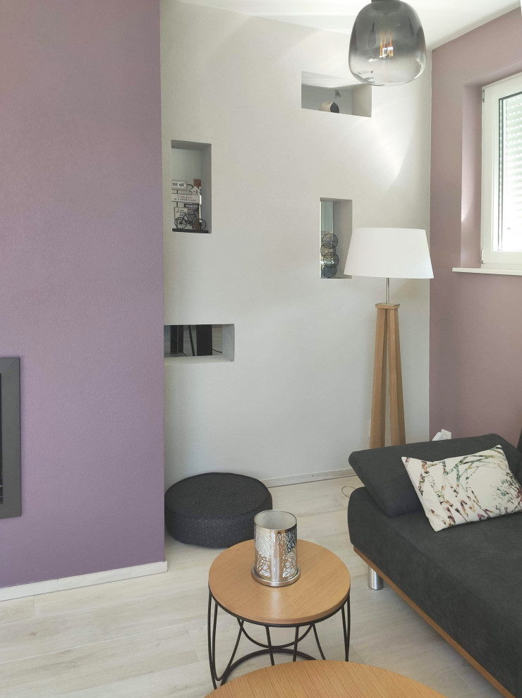 This is an example of a mid-sized modern open concept living room in Marseille with purple walls, light hardwood floors, a standard fireplace, a plaster fireplace surround, a freestanding tv and beige floor.
