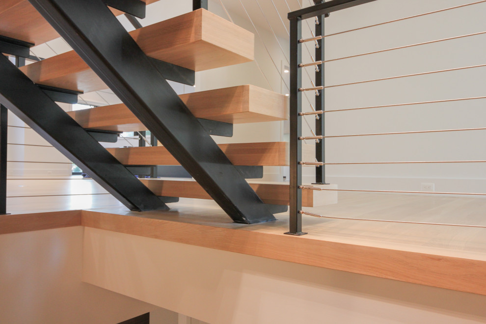 Идея дизайна: большая лестница на больцах в стиле фьюжн с деревянными ступенями, металлическими перилами и кирпичными стенами