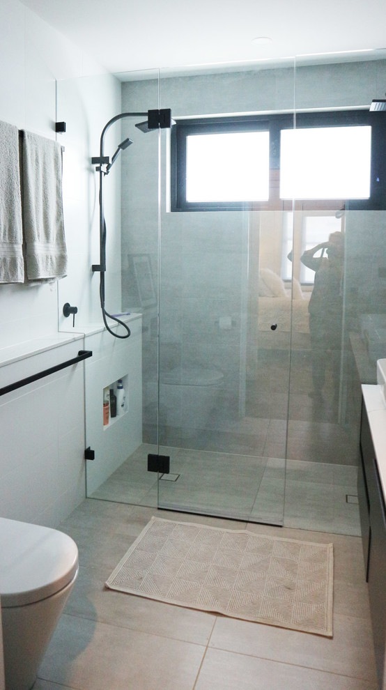 Mid-sized modern master bathroom in Sydney with flat-panel cabinets, white cabinets, a double shower, a wall-mount toilet, gray tile, porcelain tile, white walls, ceramic floors, a wall-mount sink, engineered quartz benchtops, grey floor, a hinged shower door and white benchtops.