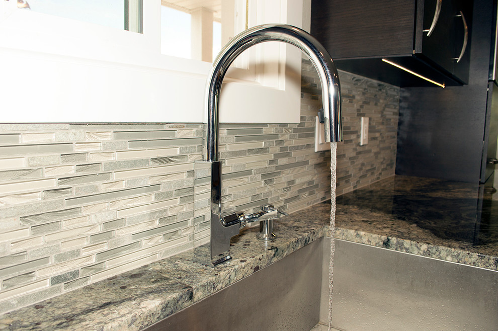 Large transitional l-shaped light wood floor eat-in kitchen photo in Seattle with an undermount sink, flat-panel cabinets, dark wood cabinets, granite countertops, green backsplash, glass tile backsplash, stainless steel appliances and an island