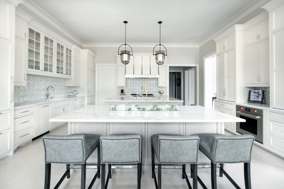 This is an example of an expansive transitional u-shaped eat-in kitchen in Nashville with an undermount sink, beaded inset cabinets, white cabinets, quartzite benchtops, white splashback, marble splashback, stainless steel appliances, marble floors, multiple islands, white floor and white benchtop.