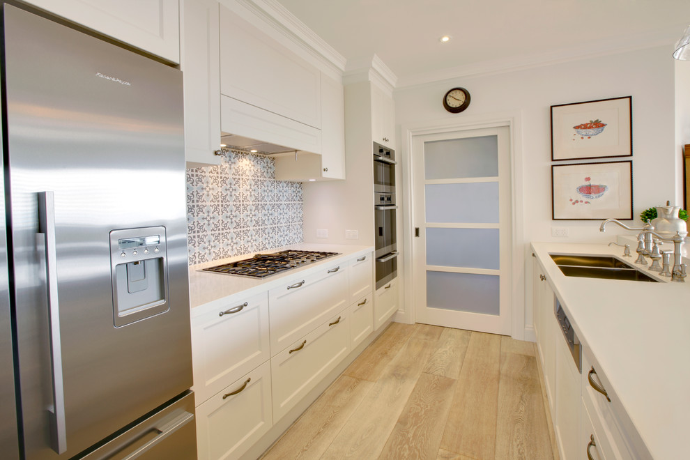 This is an example of a large beach style single-wall kitchen pantry in Melbourne with a double-bowl sink, beaded inset cabinets, white cabinets, solid surface benchtops, mosaic tile splashback, stainless steel appliances, plywood floors and with island.