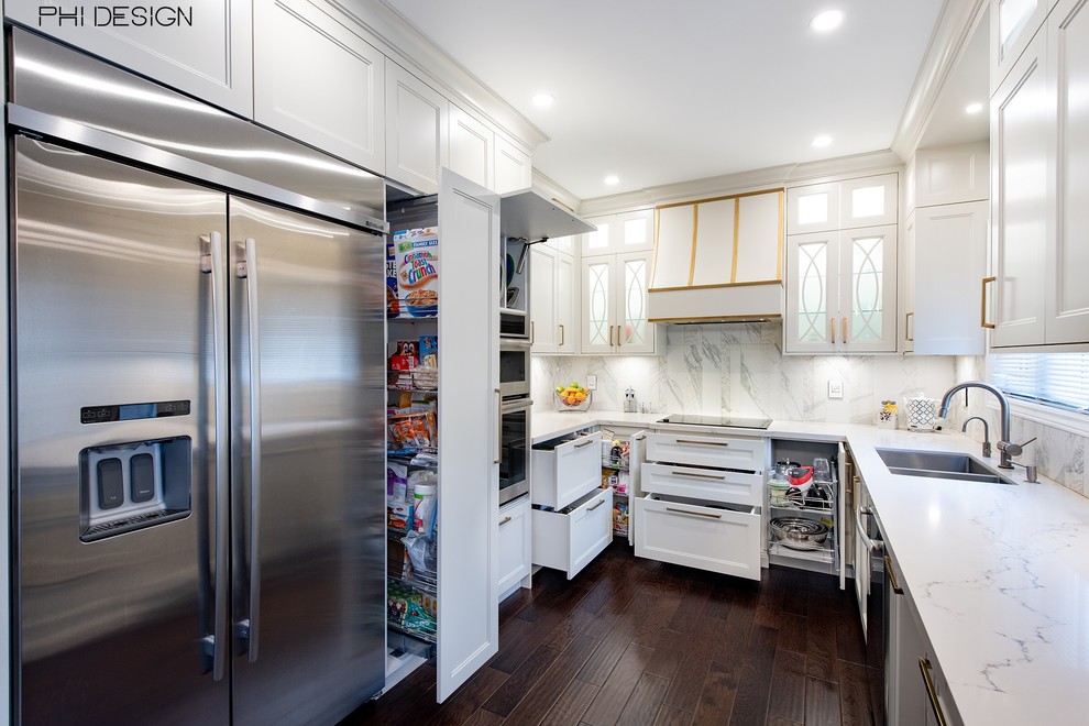 This is an example of a small transitional u-shaped eat-in kitchen in Toronto with a double-bowl sink, shaker cabinets, white cabinets, quartz benchtops, white splashback, porcelain splashback, stainless steel appliances, dark hardwood floors, a peninsula, brown floor and white benchtop.