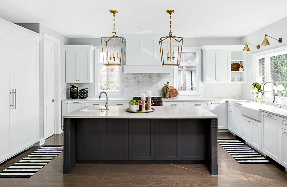 Inspiration for a transitional u-shaped kitchen in Chicago with a farmhouse sink, shaker cabinets, white cabinets, white splashback, marble splashback, panelled appliances, dark hardwood floors, with island and brown floor.