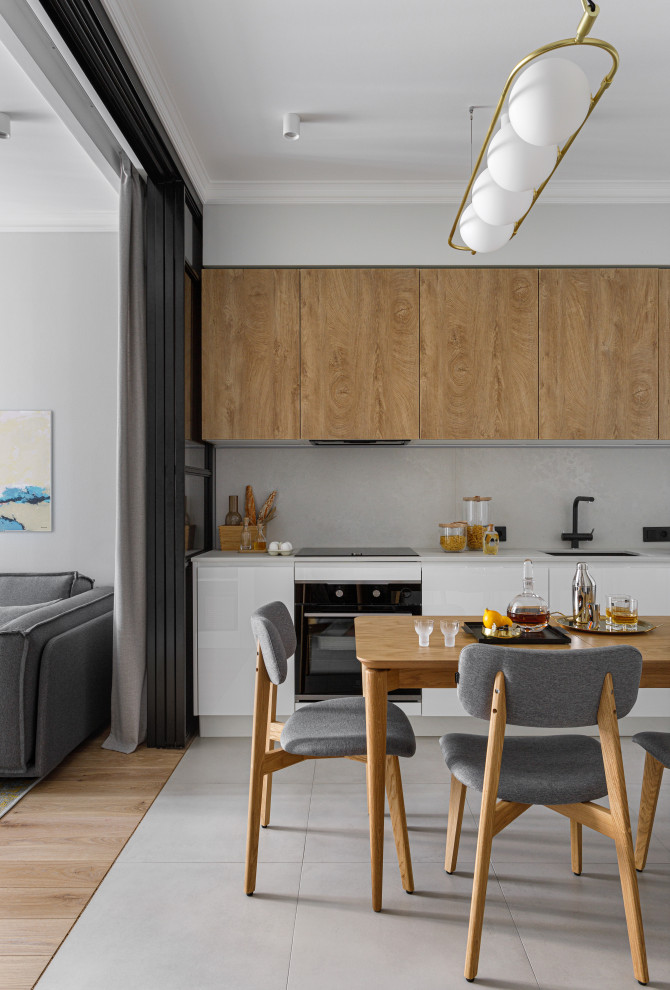 This is an example of a small contemporary l-shaped kitchen/diner in Moscow with a submerged sink, flat-panel cabinets, medium wood cabinets, engineered stone countertops, white splashback, engineered quartz splashback, black appliances, porcelain flooring, grey floors, white worktops and a feature wall.