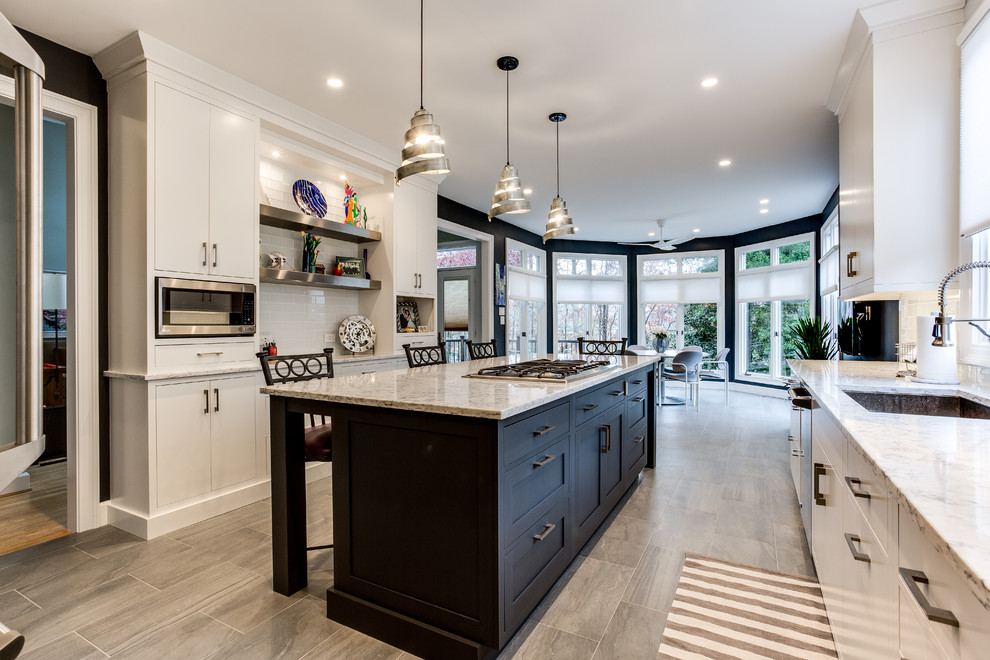 Inspiration for a transitional eat-in kitchen remodel in DC Metro with an undermount sink, flat-panel cabinets, white backsplash, stainless steel appliances, an island and glass tile backsplash