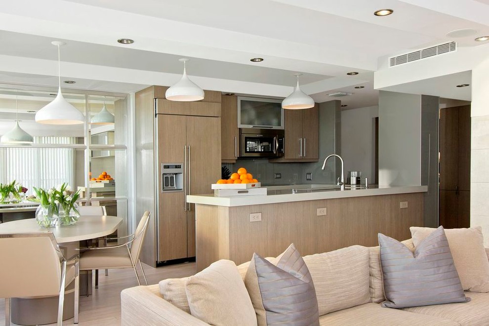 Transitional galley open plan kitchen in Miami with flat-panel cabinets, light wood cabinets and panelled appliances.