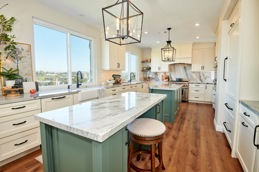 Inspiration for a large traditional galley eat-in kitchen in San Diego with a farmhouse sink, flat-panel cabinets, green cabinets, quartzite benchtops, grey splashback, stone slab splashback, stainless steel appliances, vinyl floors, multiple islands, brown floor and grey benchtop.