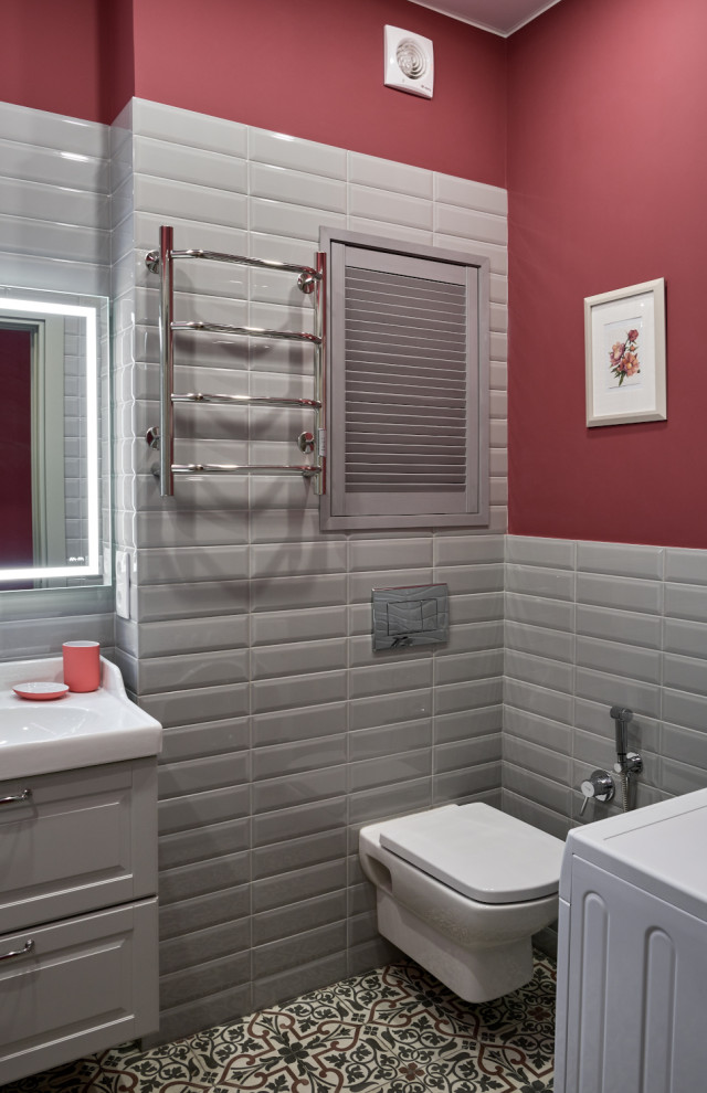 На фото: туалет среднего размера в современном стиле с фасадами с выступающей филенкой, серыми фасадами, инсталляцией, серой плиткой, керамической плиткой, розовыми стенами, полом из цементной плитки, подвесной раковиной, разноцветным полом и подвесной тумбой