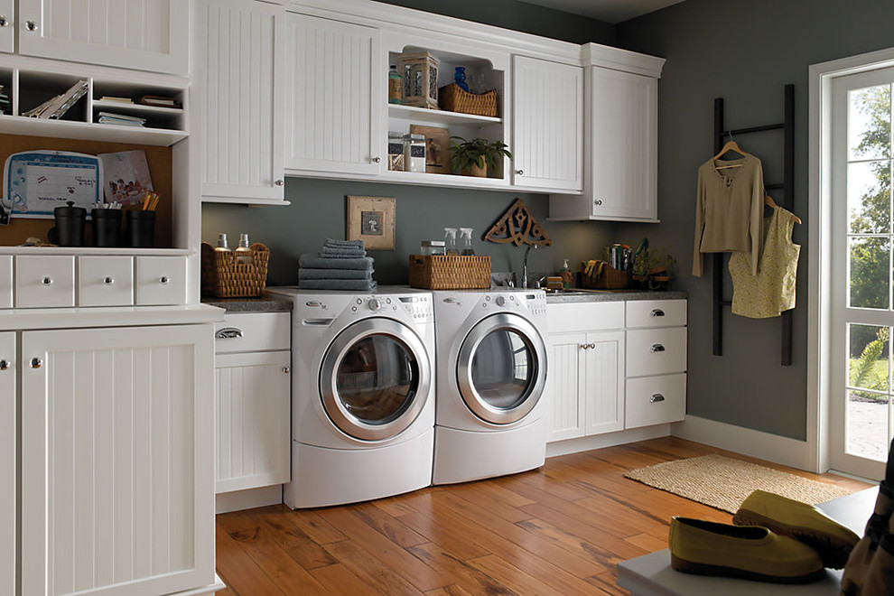 Design ideas for a large traditional single-wall utility room in Baltimore with a drop-in sink, white cabinets, granite benchtops, grey walls, medium hardwood floors and a side-by-side washer and dryer.