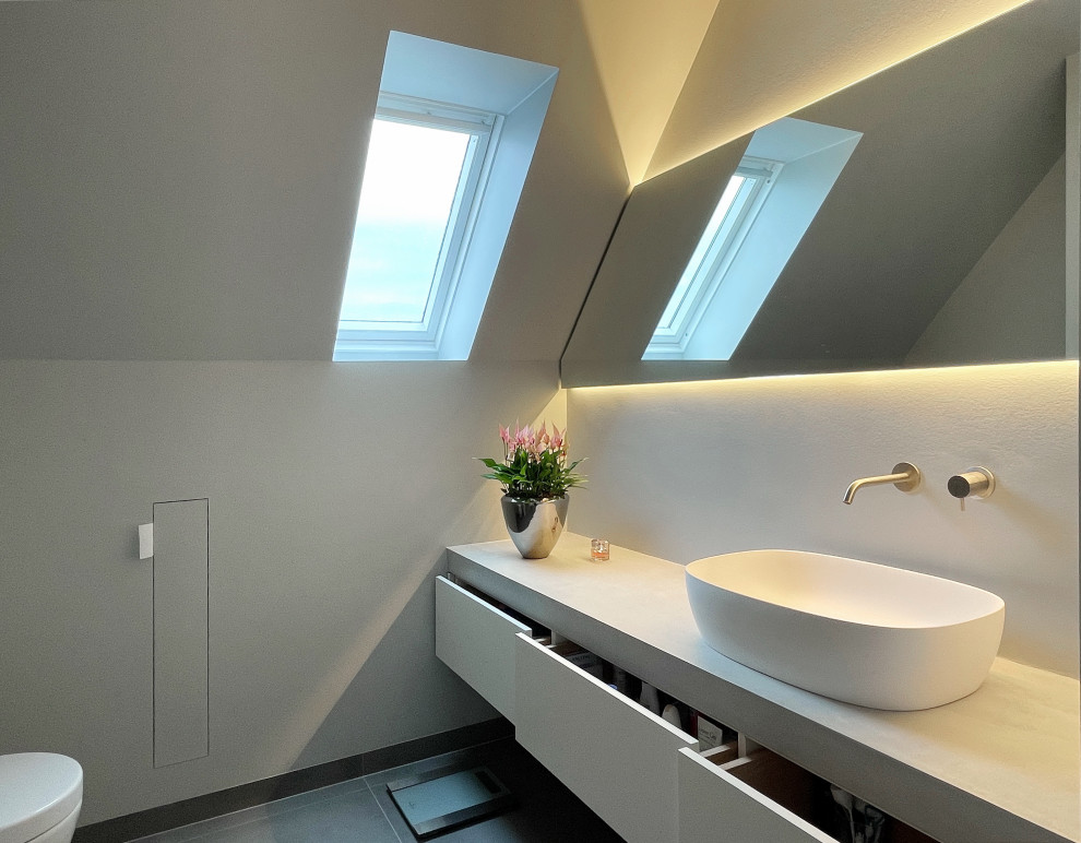 Inspiration for a mid-sized contemporary 3/4 wet room bathroom in Dusseldorf with flat-panel cabinets, white cabinets, a wall-mount toilet, gray tile, grey walls, ceramic floors, a vessel sink, grey floor, a hinged shower door, grey benchtops, a single vanity and a freestanding vanity.