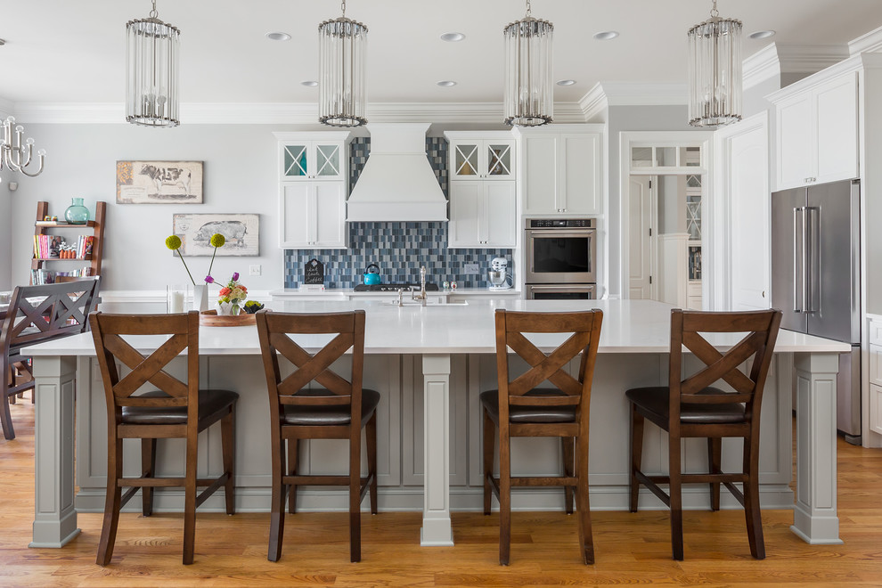 Large transitional l-shaped medium tone wood floor open concept kitchen photo in Raleigh with a farmhouse sink, flat-panel cabinets, white cabinets, quartz countertops, blue backsplash, glass tile backsplash, stainless steel appliances and an island
