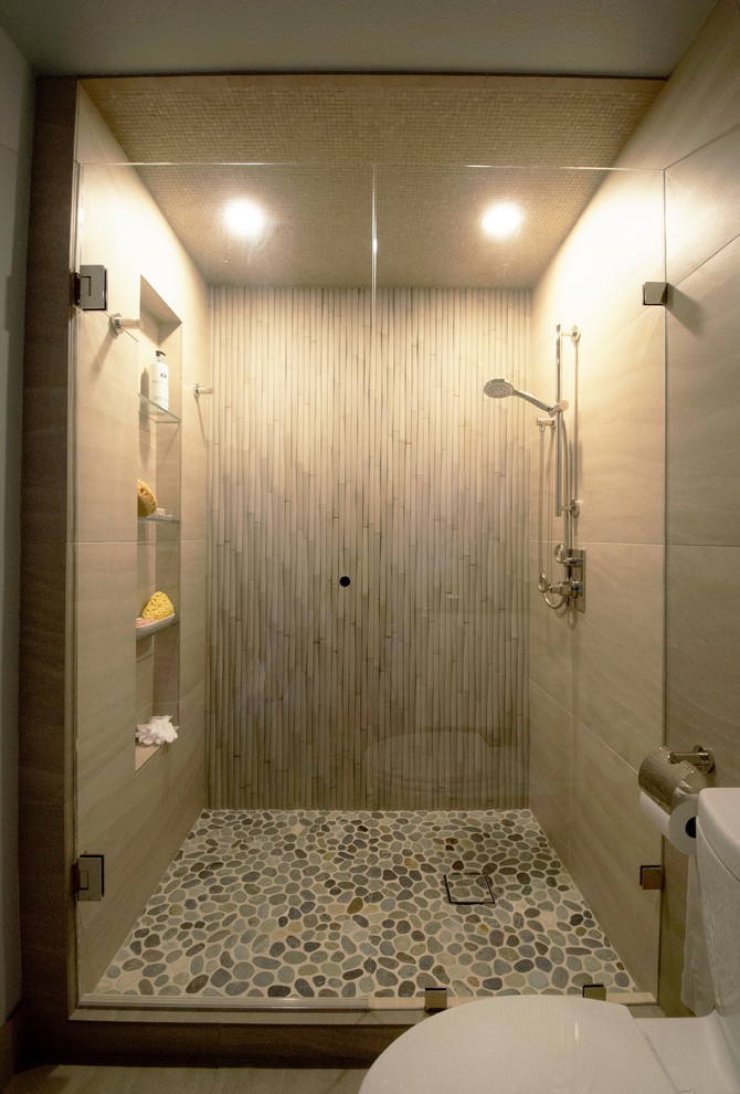 Inspiration for a mid-sized contemporary bathroom in Denver with flat-panel cabinets, white cabinets, an alcove shower, a two-piece toilet, beige tile, porcelain tile, green walls, porcelain floors, an integrated sink, glass benchtops, beige floor and a hinged shower door.