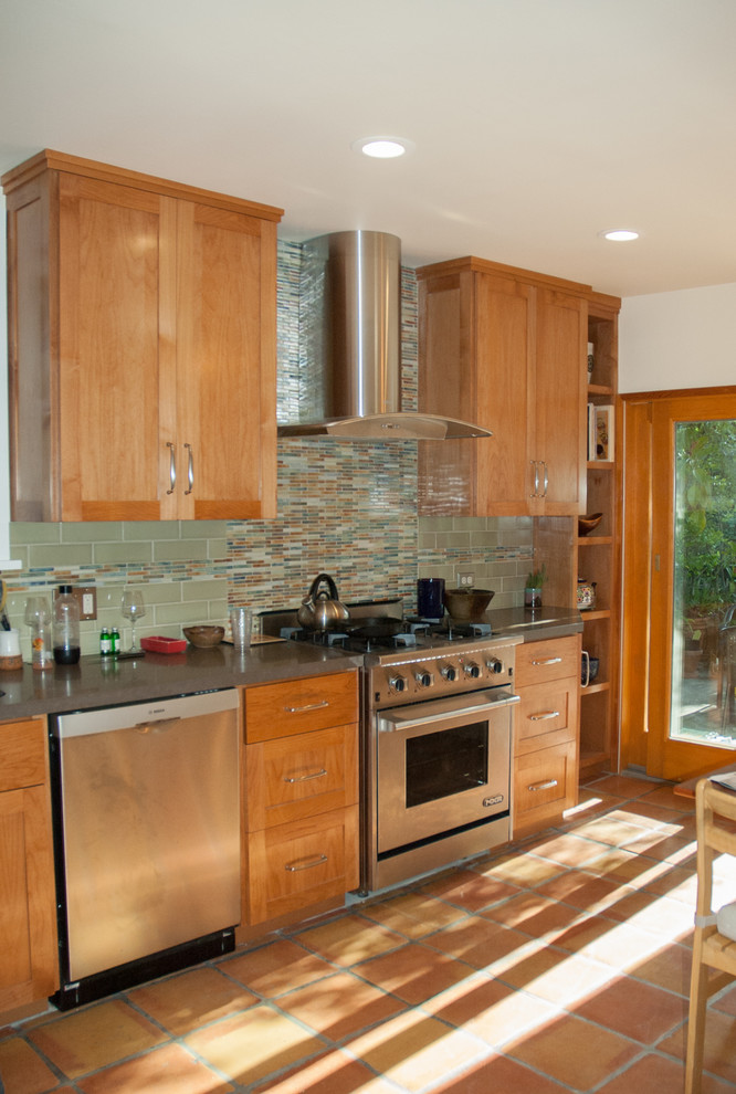 This is an example of a mid-sized transitional l-shaped separate kitchen in San Francisco with shaker cabinets, light wood cabinets, green splashback, ceramic splashback, stainless steel appliances, terra-cotta floors, no island, concrete benchtops, orange floor and grey benchtop.