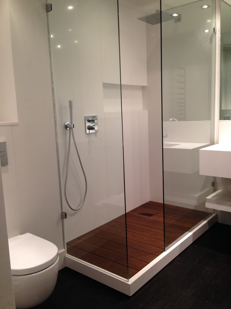 This is an example of a mid-sized contemporary 3/4 bathroom in Barcelona with a corner shower, a wall-mount toilet, white walls and an integrated sink.