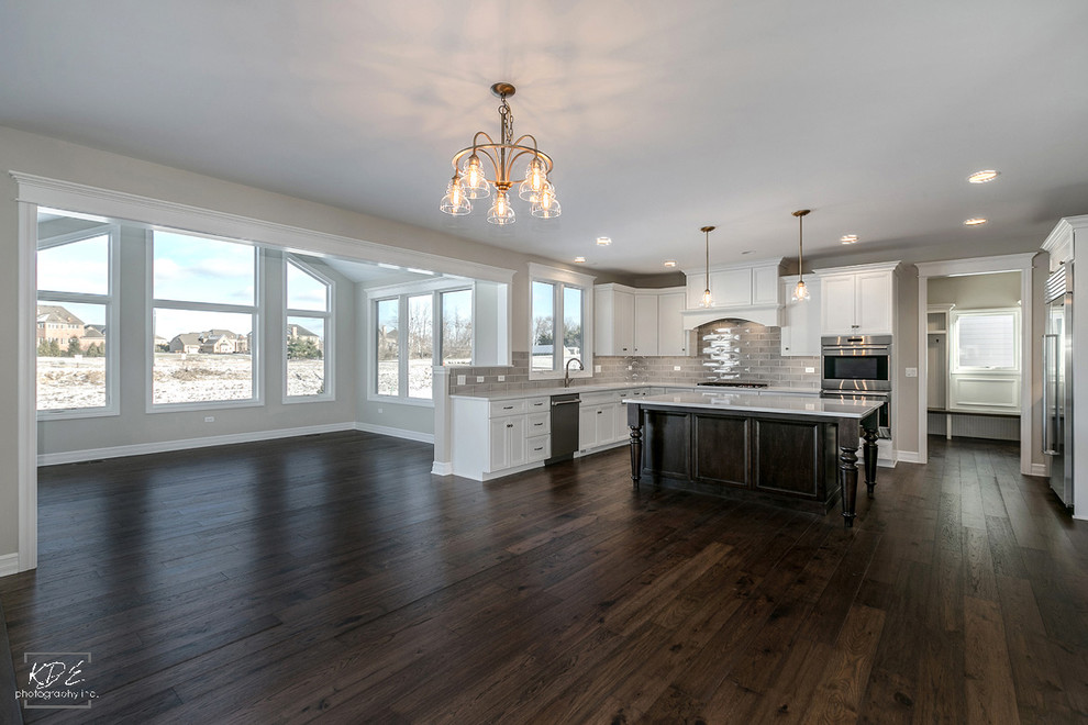 Eat-in kitchen - large transitional u-shaped medium tone wood floor eat-in kitchen idea in Chicago with an undermount sink, white cabinets, quartzite countertops, gray backsplash, stainless steel appliances and an island