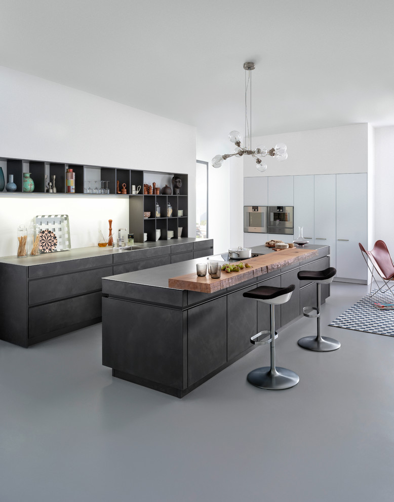 Photo of a mid-sized modern l-shaped open plan kitchen in New York with an undermount sink, flat-panel cabinets, grey cabinets, concrete benchtops, white splashback, stainless steel appliances, concrete floors and with island.