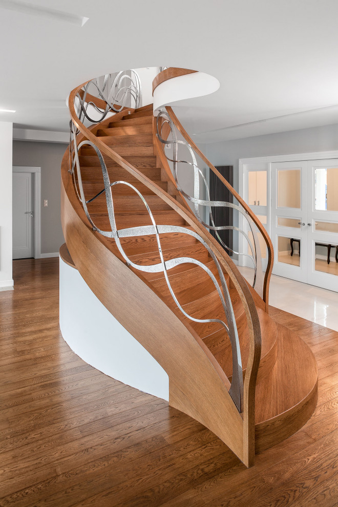 Идея дизайна: изогнутая деревянная лестница в современном стиле с деревянными ступенями и металлическими перилами