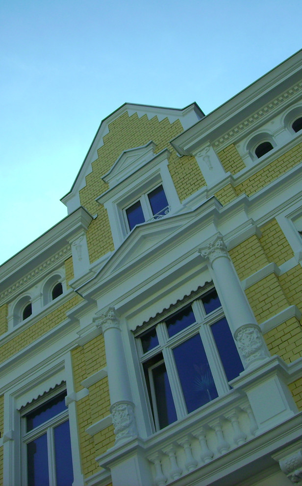 Mittelgroßes, Dreistöckiges Klassisches Haus mit Putzfassade, gelber Fassadenfarbe und Satteldach in Sonstige