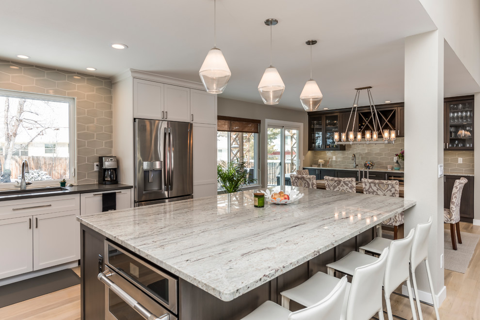Large transitional light wood floor open concept kitchen photo in Denver with an undermount sink, shaker cabinets, gray cabinets, granite countertops, gray backsplash, ceramic backsplash, stainless steel appliances, an island and white countertops