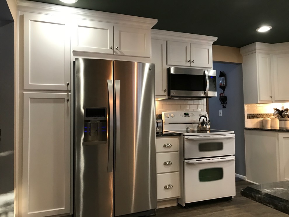 Inspiration for a mid-sized transitional u-shaped medium tone wood floor eat-in kitchen remodel in New York with a double-bowl sink, shaker cabinets, white cabinets, granite countertops, white backsplash, subway tile backsplash and stainless steel appliances