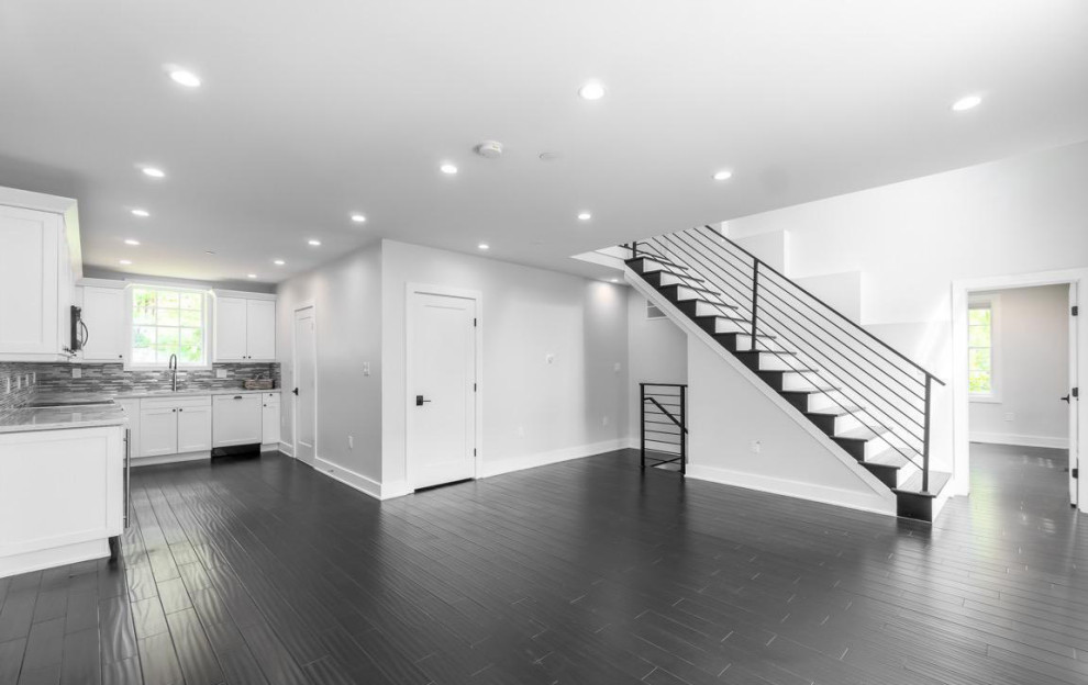 This is an example of a contemporary open plan living room in DC Metro with white walls, dark hardwood flooring and black floors.