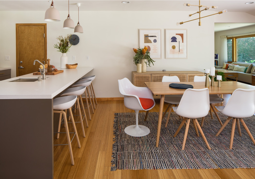 Inspiration for a mid-sized scandinavian kitchen/dining combo in Los Angeles with white walls, bamboo floors, a standard fireplace, a tile fireplace surround and yellow floor.