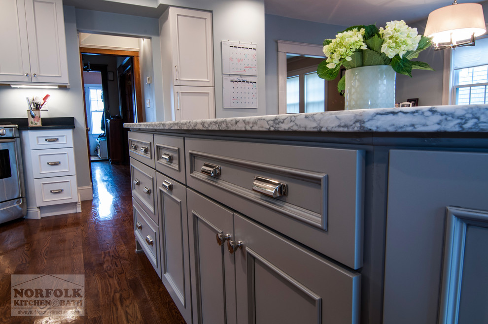 Inspiration for a transitional l-shaped medium tone wood floor open concept kitchen remodel in Boston with a single-bowl sink, recessed-panel cabinets, white cabinets, quartzite countertops, stainless steel appliances and an island