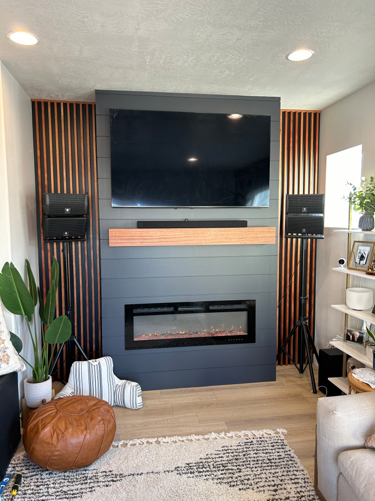 This is an example of a living room in Salt Lake City with blue walls, a standard fireplace, a wall-mounted tv and panelled walls.