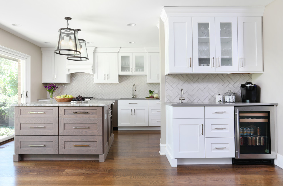 Inspiration for a large transitional u-shaped eat-in kitchen in Chicago with an undermount sink, white cabinets, grey splashback, ceramic splashback, with island, brown floor, grey benchtop, recessed-panel cabinets, quartzite benchtops, stainless steel appliances and medium hardwood floors.